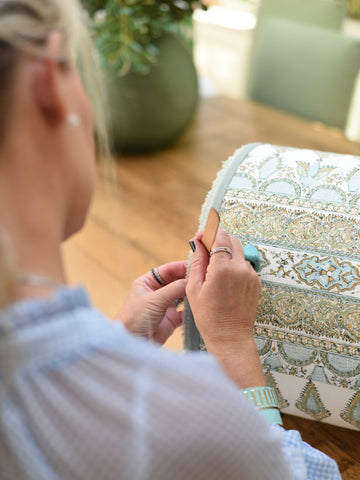 Person holding a decorative lampshade with intricate patterns in a home setting