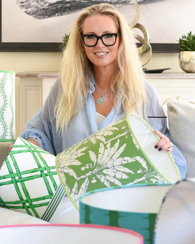 Woman holding green and white patterned lampshades in a home setting