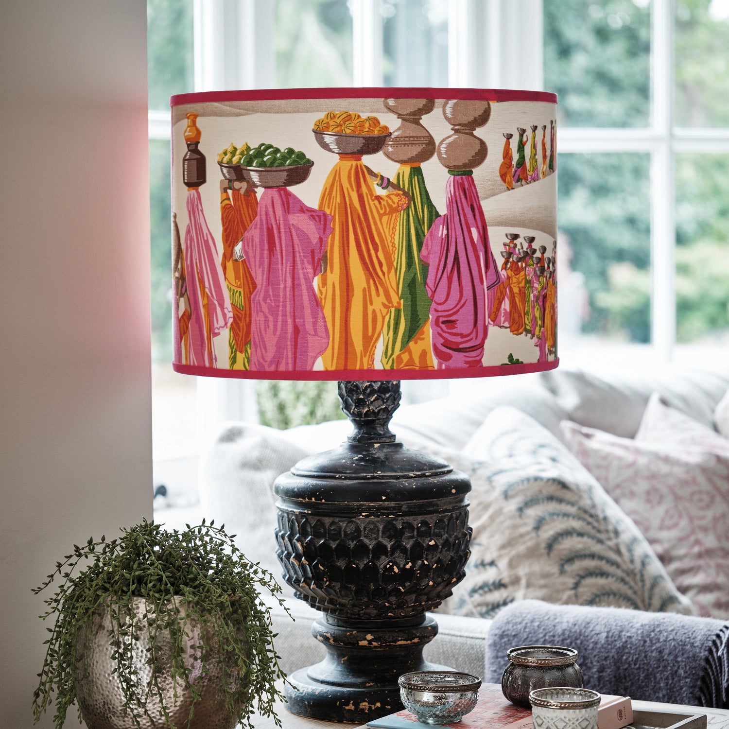 Decorative lamp with colorful shade featuring people in traditional attire, placed on a table.